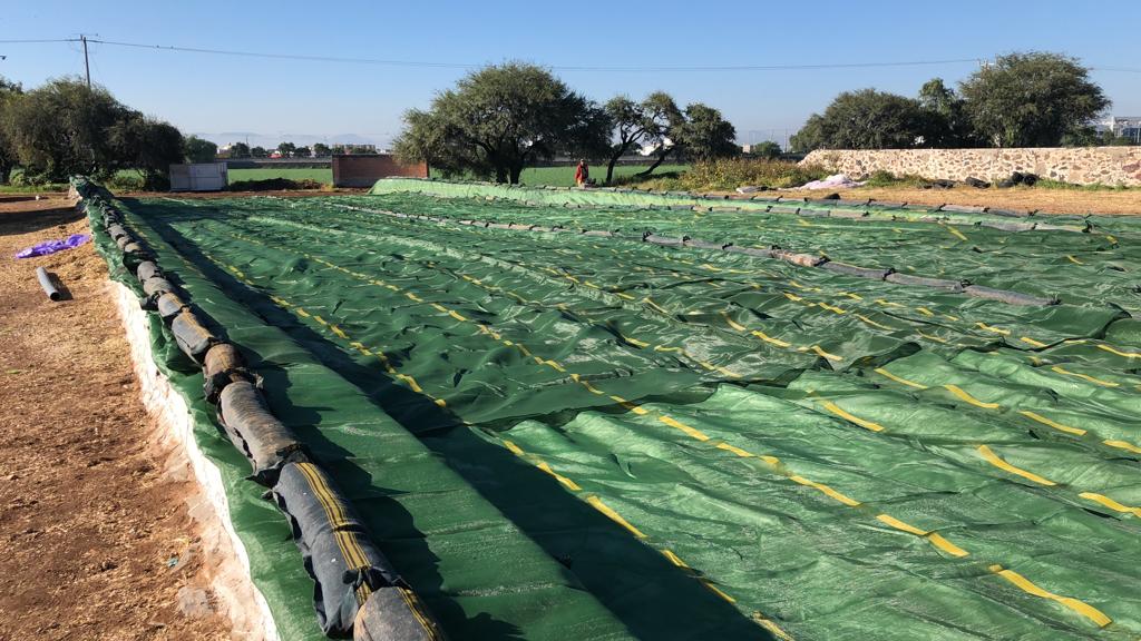 Fotografía de una malla para cubiertas de silos color verde extendida a lo largo en el exterior en una granja.